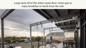 Eine große Terrasse mit Sitzgelegenheiten im Freien und Blick auf den Parkplatz.
