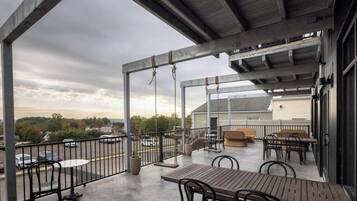 Eine große Terrasse mit Sitzgelegenheiten im Freien und Blick auf den Parkplatz.