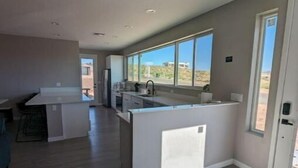 Een moderne keuken met een centraal eiland, grote ramen en uitzicht op de woestijn.