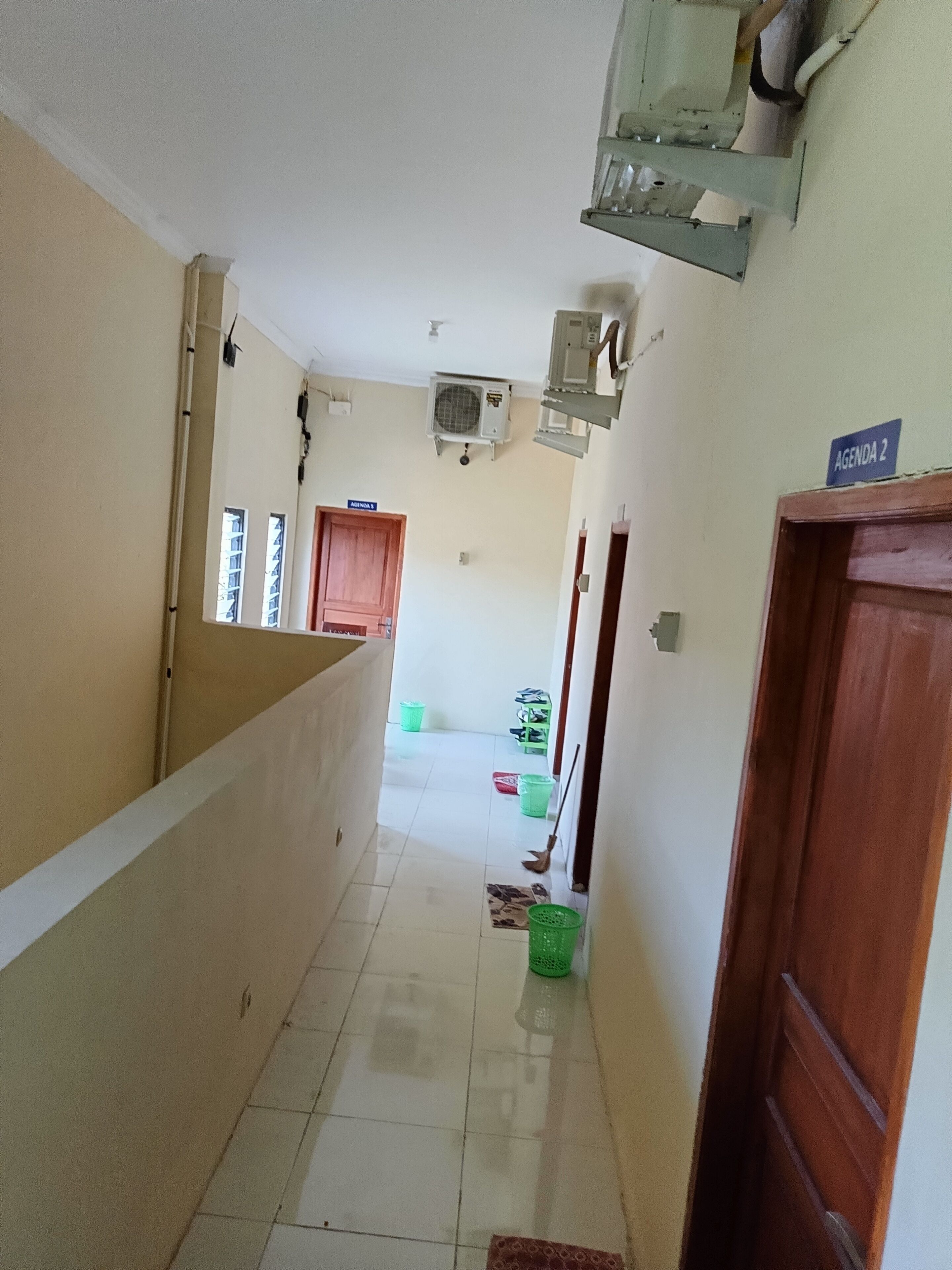 A corridor with a tiled floor, a wooden door labeled "AGENDA 2", and a ceiling fan.