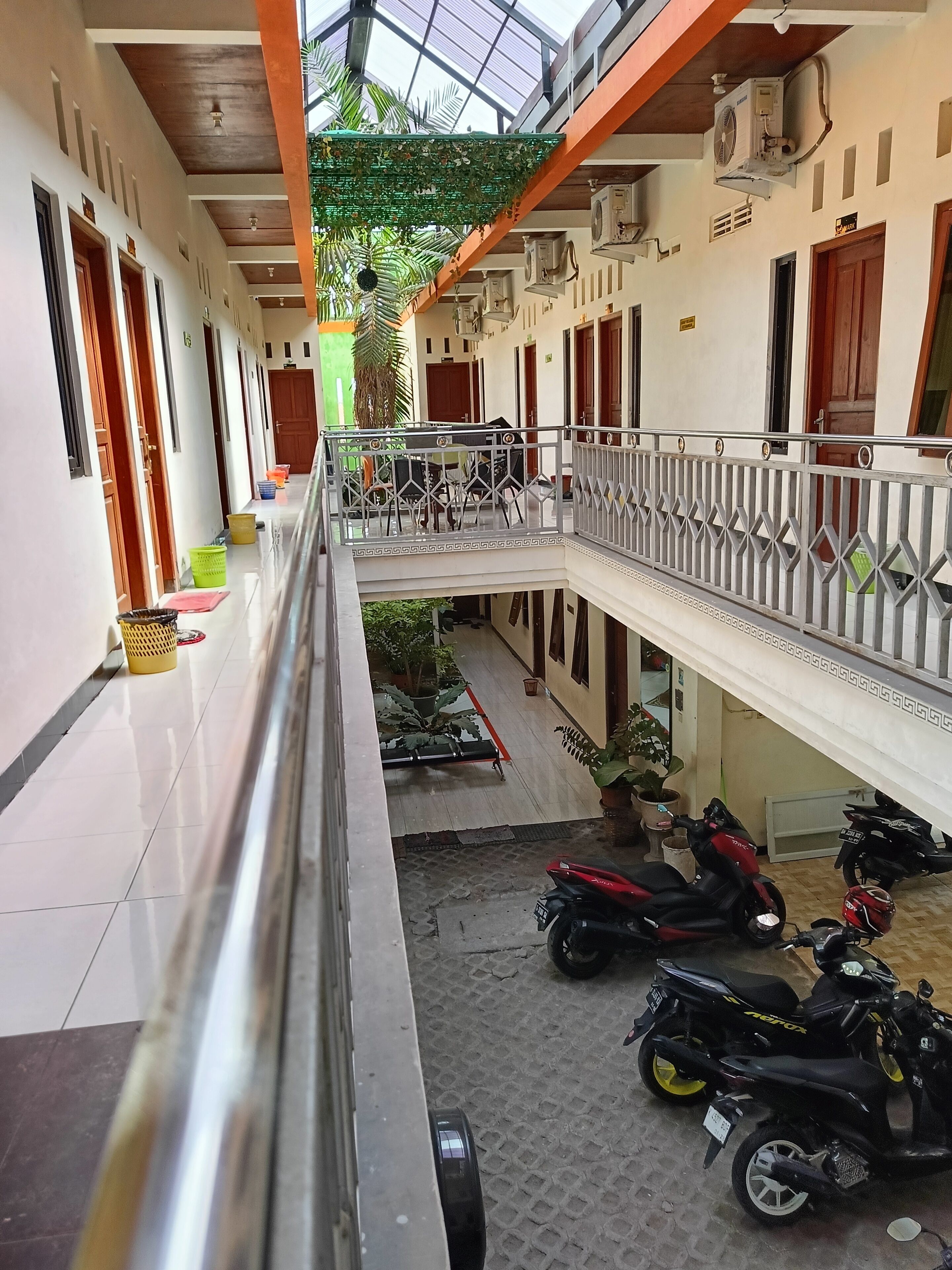 A multi-level building with a covered walkway, potted plants, and parked motorcycles.