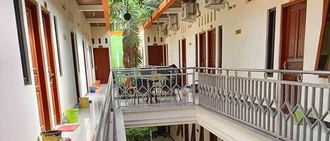 A multi-level building with a covered walkway, potted plants, and parked motorcycles.