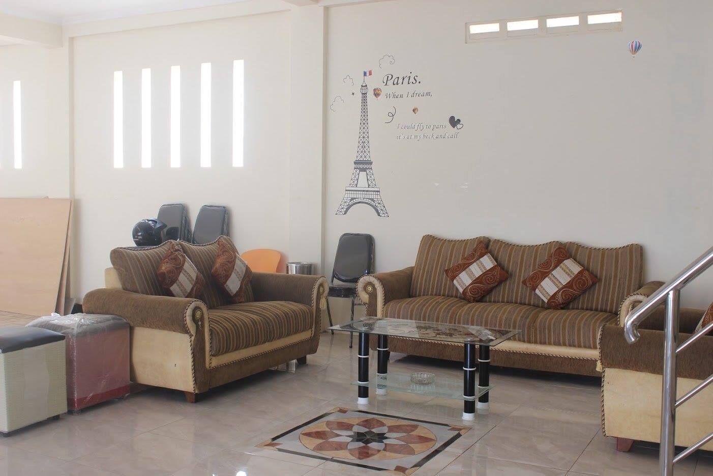 A living room with two sofas, a glass coffee table, and a decorative wall with a Paris-themed design.