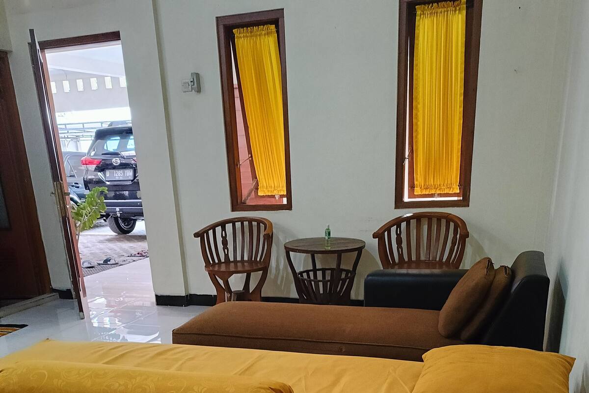 Une chambre d’hôtel avec un lit, deux chaises, une petite table et un canapé.