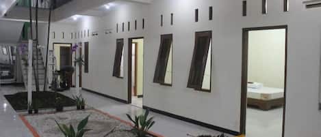 A spacious hotel lobby with a central seating area, multiple doors, and a staircase leading to an upper level.