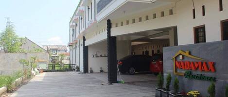A residential building with a garage entrance, a sign reading "NADAMAX Residence," and potted plants.