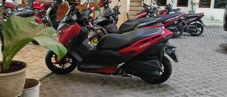 A covered parking area with multiple motorcycles parked.