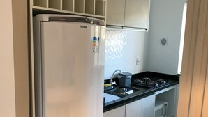 Moderni keittiö, jossa on ruostumattomasta teräksestä valmistettu jääkaappi, mikroaaltouuni ja kaasuliesi.