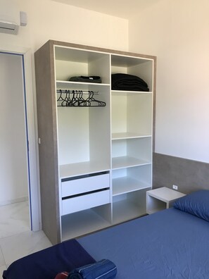 A bedroom with a bed, a wardrobe, and a nightstand. - Apartamento Próximo ao Beto Carrero (Praia de Armação do Itapocorói Penha)