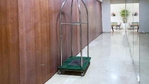Un couloir avec un mur en bois, une étagère en métal et un tapis vert sur le sol.