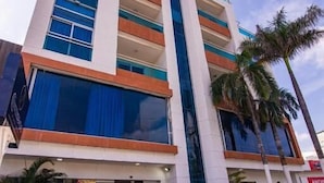 Un hôtel moderne doté d’une entrée centrale, de plusieurs étages et d’un trottoir dallé.