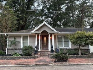 A two-story house with a front porch, a mailbox, and a small garden area.