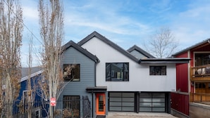 Ein modernes, zweistöckiges Haus mit Garage, roter Tür und einem Metallzaun.