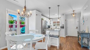 Una cocina moderna con armarios blancos, una isla central e iluminación colgante.