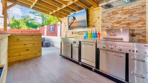 Una cocina moderna con un revoque de ladrillo, electrodomésticos de acero inoxidable y techo de madera.