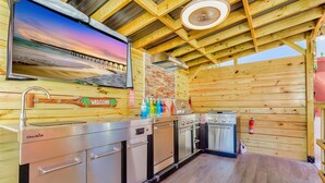 Una cabaña de madera con kitchenette, un televisor montado en la pared y vistas a un muelle.