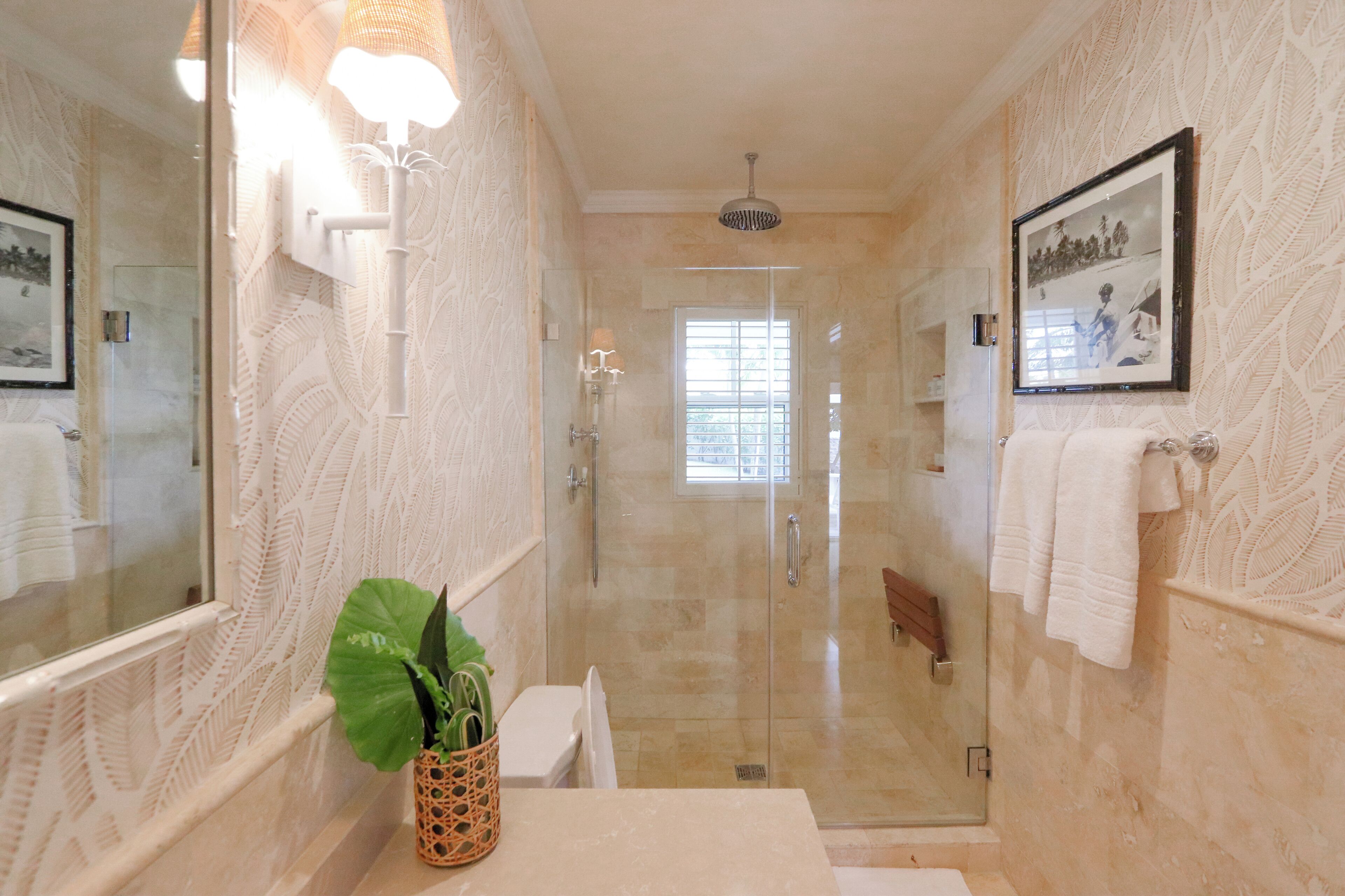Un bagno con doccia vetrata, uno specchio grande e un quadro appeso al muro.