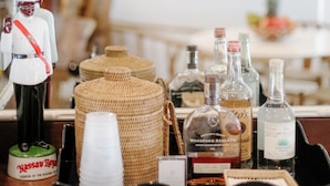 A bar area with a decorative soldier figurine, wicker baskets, and various bottles of liquor. - The Rock House Hotel (Dunmore Town)