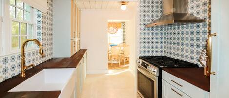 A kitchen with white cabinets, a black stove, and a sink.