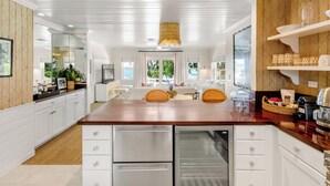 A modern kitchen with white cabinetry, a wooden countertop, and a built-in refrigerator. - The Rock House Hotel (Dunmore Town)