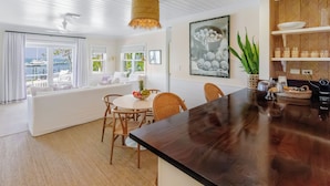A modern kitchen with a dark wooden island, white cabinetry, and a large window overlooking a marina. - The Rock House Hotel (Dunmore Town)