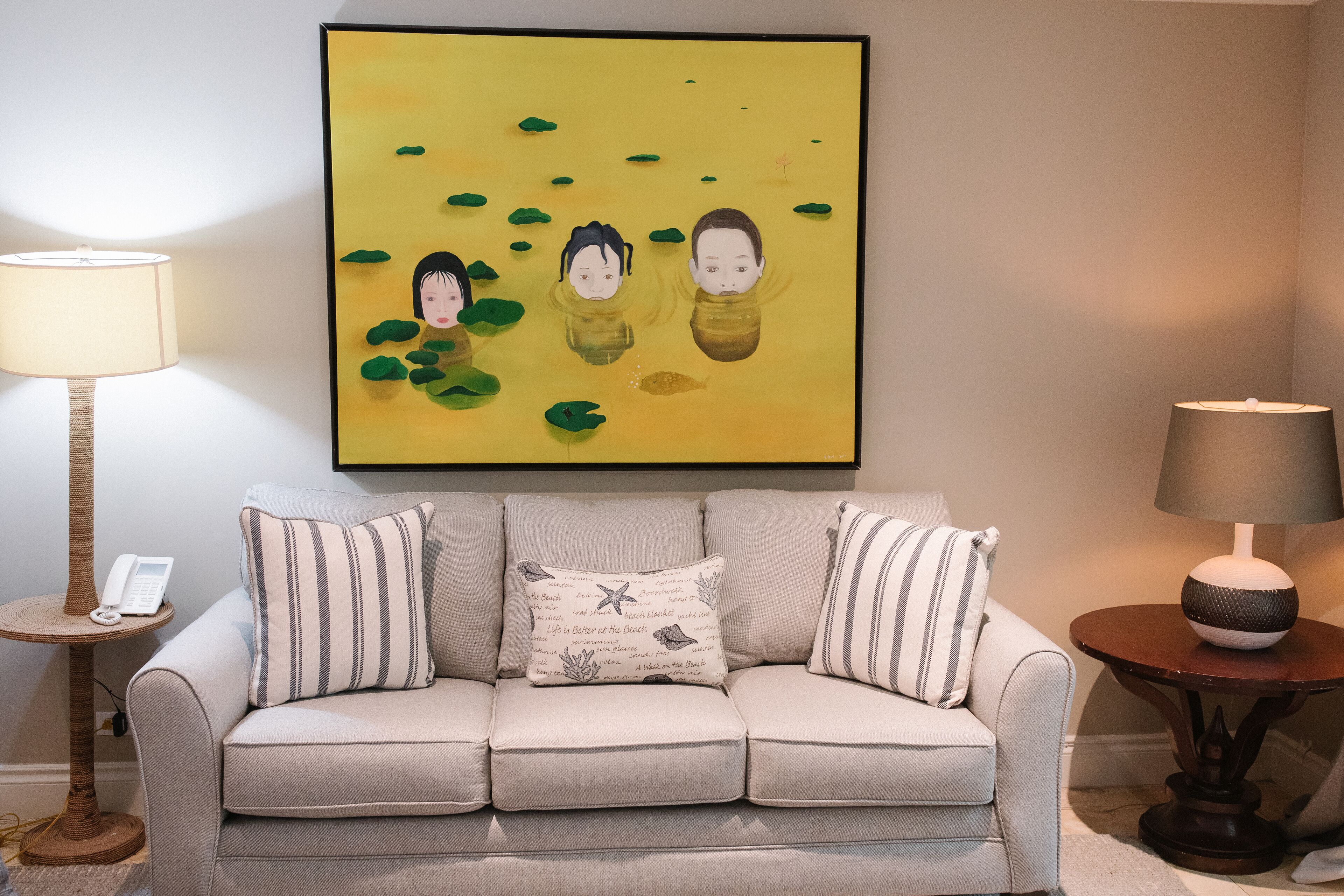 A living room with a sofa, two lamps, and a framed artwork on the wall.