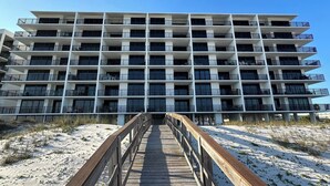 Un hotel de varios pisos con una pasarela de madera que conduce a la entrada.