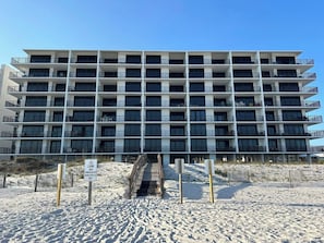 Un hotel de varios pisos con balcones, acceso directo a la playa y cielo despejado.