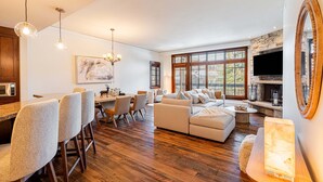 A spacious living area with a fireplace, dining area, and large windows. - Luxury Resort Living, Private Hot tub with 2 Master BD (Park City)