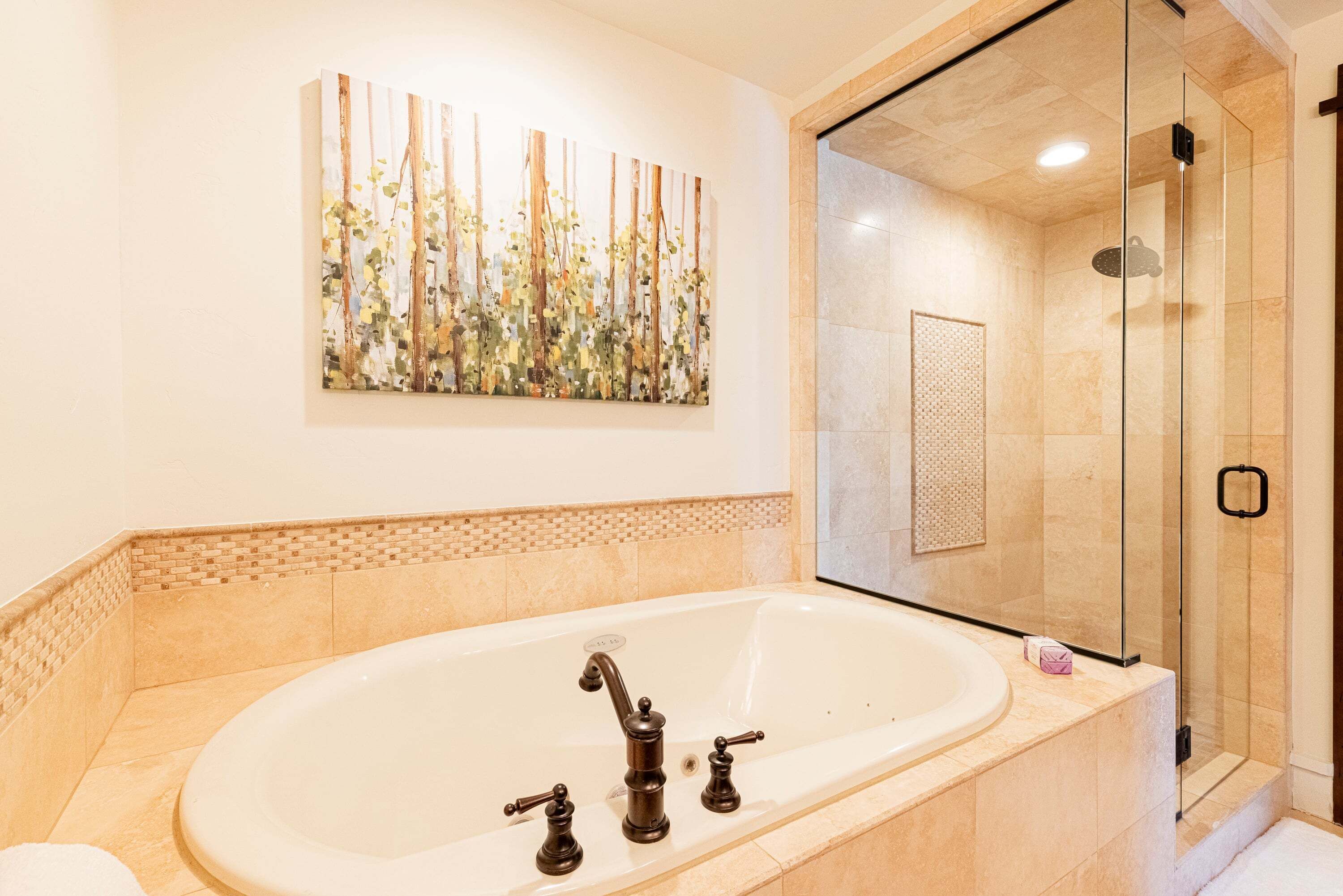 A modern bathroom with a freestanding bathtub, a glass shower enclosure, and a wall-mounted artwork.