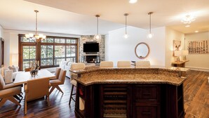 A spacious kitchen with a large island, a dining area with chairs, a fireplace, and a stone accent wall. - Luxury Resort Living, Private Hot tub with 2 Master BD (Park City)