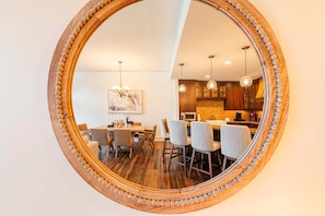 A dining area with a wooden table and chairs, a chandelier, and a kitchen visible through a large mirror. - Luxury Resort Living, Private Hot tub with 2 Master BD (Park City)