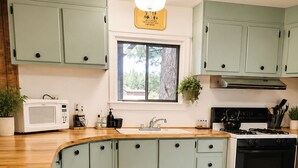 A kitchen with light green cabinets, a white stove, and a wooden countertop. - Quiet Escape for Hunters & Family Retreats! (Alpine)