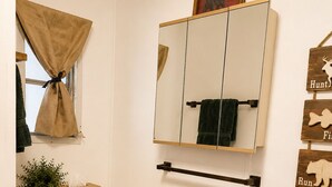 A bathroom with a mirror, towel rack, storage bins, and a bear crossing sign. - Quiet Escape for Hunters & Family Retreats! (Alpine)