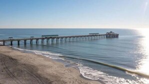 A beach with a wooden pier extending into calm waters. - Folliday Inn: The Torpedo: Room 22 (Folly Beach)