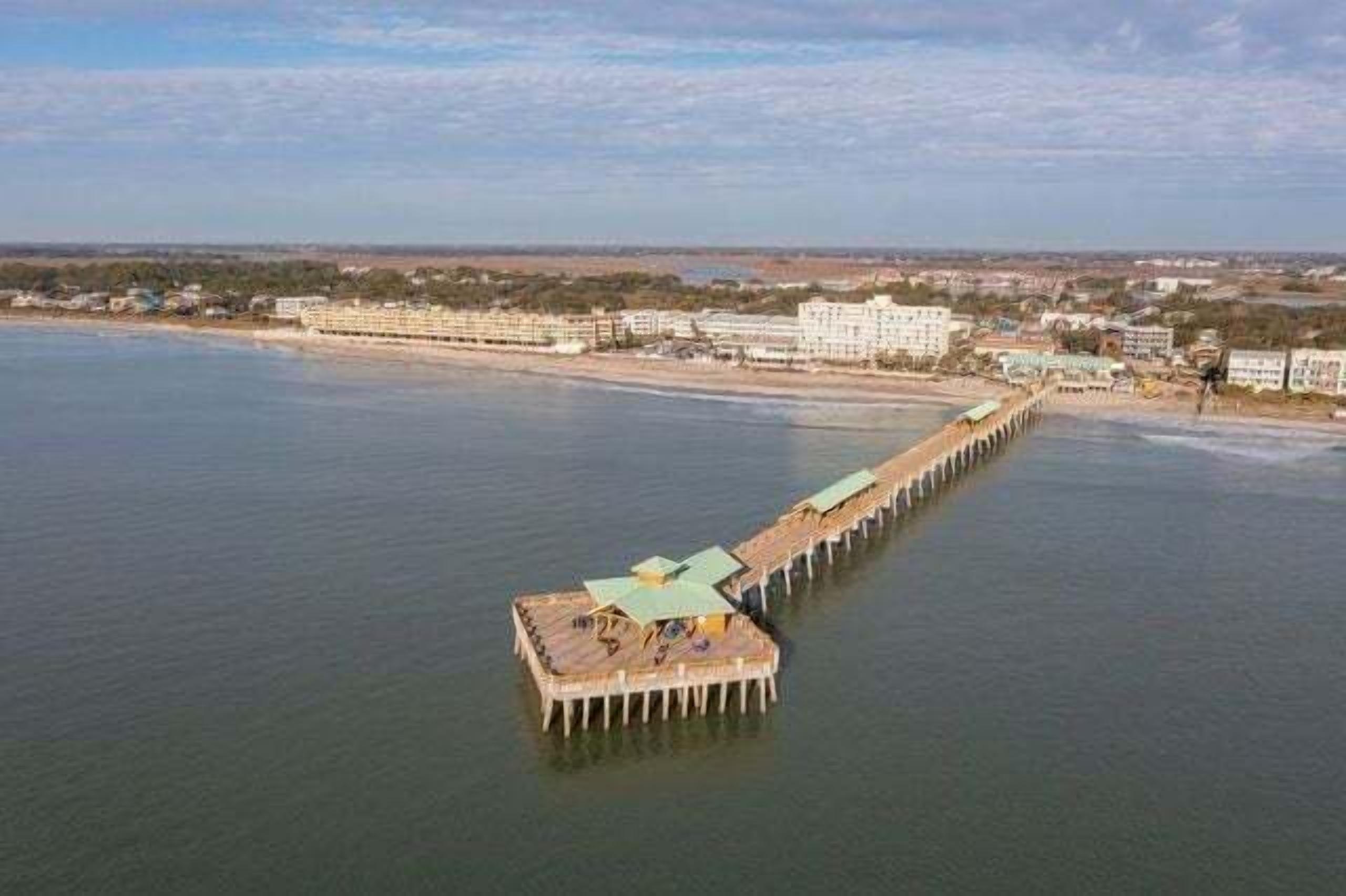 A pier extending into a body of water with buildings on the shore.