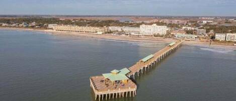 A pier extending into a body of water with buildings on the shore.