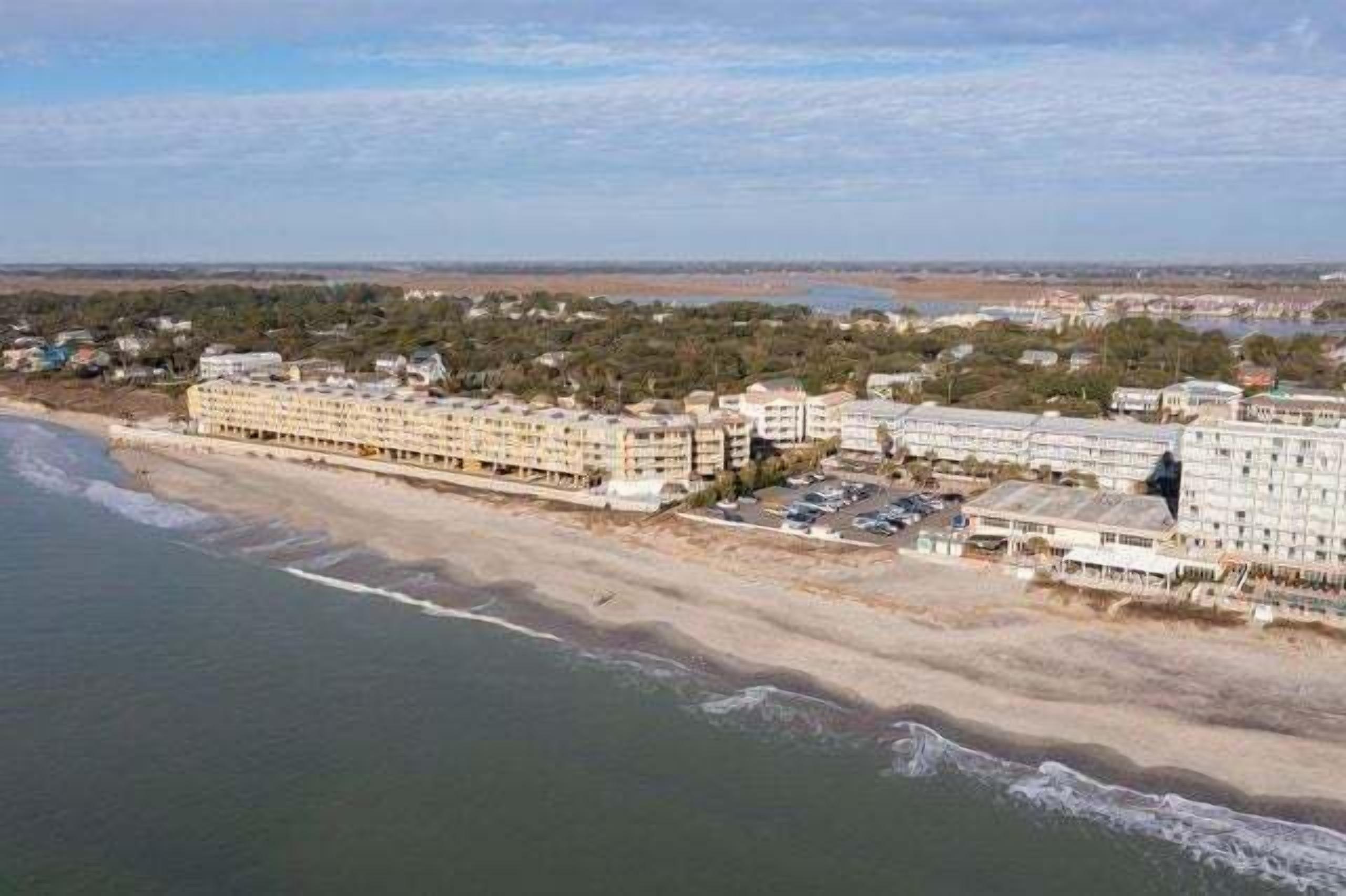 Un hotel frente al mar, con varias construcciones, una playa y vistas al océano.