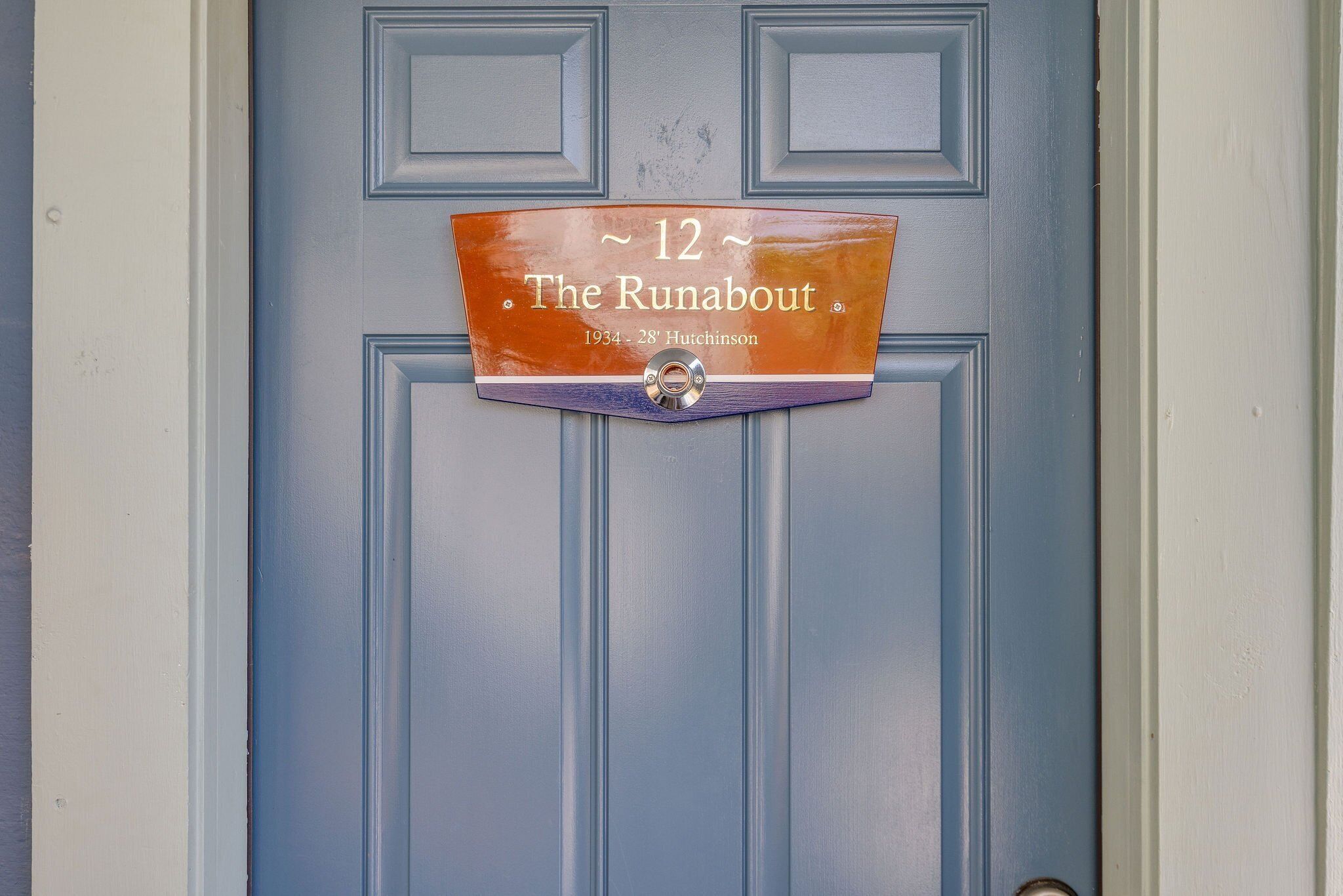 Een blauwe deur met een bord waarop staat: The Runabout, 1934, 28 Hutchinson.