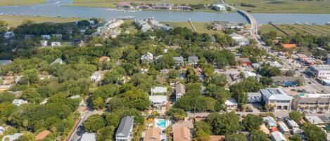 An aerial view of a coastal town with a marina, residential areas, and a prominent hotel with a swimming pool.