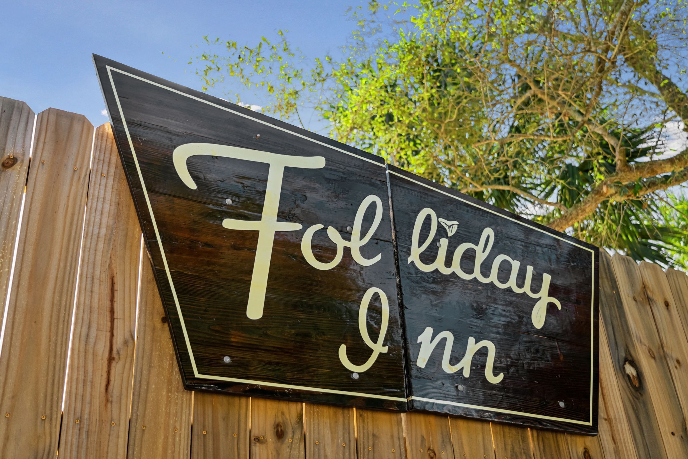 A wooden sign with the text "Folk day Inn" on a fence.