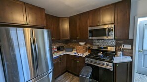 A kitchen with wooden cabinets, stainless steel appliances, a microwave, and a stove. - Platte River Cabin @ Pine -Main (Pine)