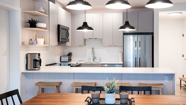 A modern kitchen with white cabinets, stainless steel appliances, and pendant lighting. - Farwell's Spike by Revelstoke Vacations (Revelstoke)