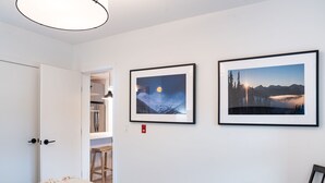 A bedroom with a bed, a chair, and two framed pictures on the wall. - Farwell's Spike by Revelstoke Vacations (Revelstoke)