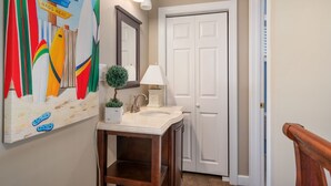 A bathroom with a sink, mirror, and a wall-mounted light fixture. - Sunwatch: Soundfront, Hot Tub, Private Boat Dock and Community Pool Access (Nags Head)