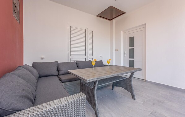 A modern outdoor living area with a grey sectional sofa, a wicker table, and two drinks on the table.