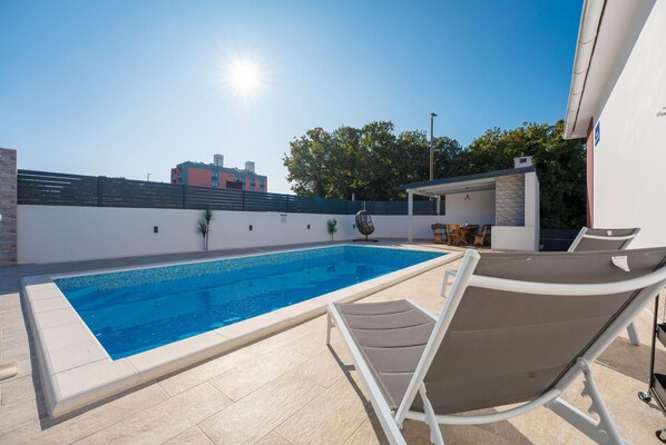 Relax by the pool surrounded by a tranquil outdoor space with a clear pool and comfortable lounge seating.