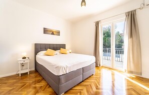 Relax in a spacious room with a large bed, wooden floor, and sliding door leading to an outdoor area with a view.
