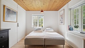 A bedroom with a wooden ceiling, a bed with two pillows, a window, and a radiator. - Gorgeous home in Næstved (Næstved)