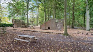 A rustic wooden cabin in a forested area with a picnic table in the foreground. - Gorgeous home in Næstved (Næstved)